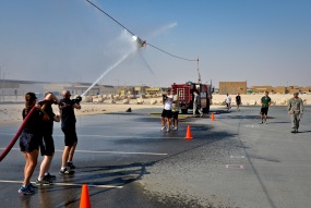 Service members participate in a fire muster event at the 379th Air Expeditionary Wing in Southwest Asia, Sept. 28, 2013. Teams had to get the bucket past their opponents cone by blasting the bucket with water during this event. More than 80 service members in 20 teams pitted their might in a firefighting flavored challenge wrestling everything from hoses and tires to water buckets and fire trucks. (U.S. Air Force photo/Staff Sgt. Benjamin W. Stratton)